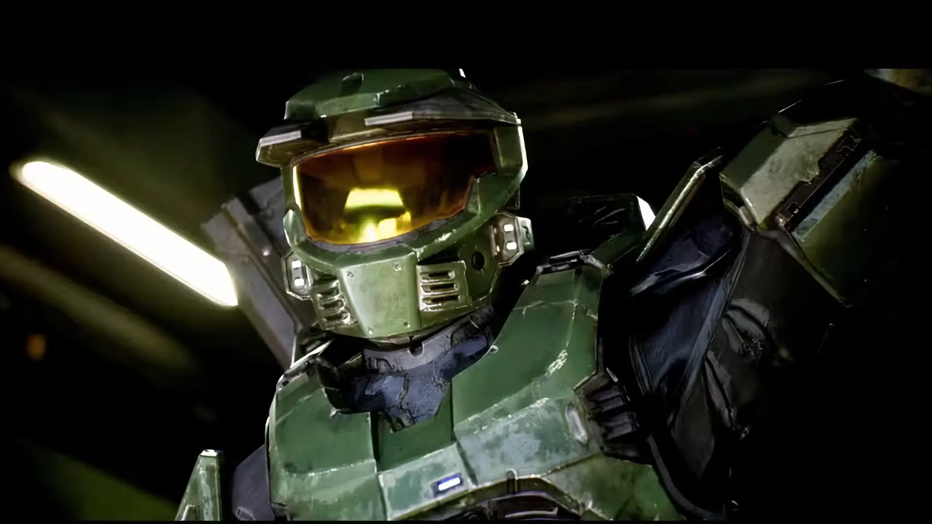 Tuvplāns ar Master Chief zaļajā tērauda bruņuķiverē un tās mirdzošo zelta vizieri tumšā vidē.
