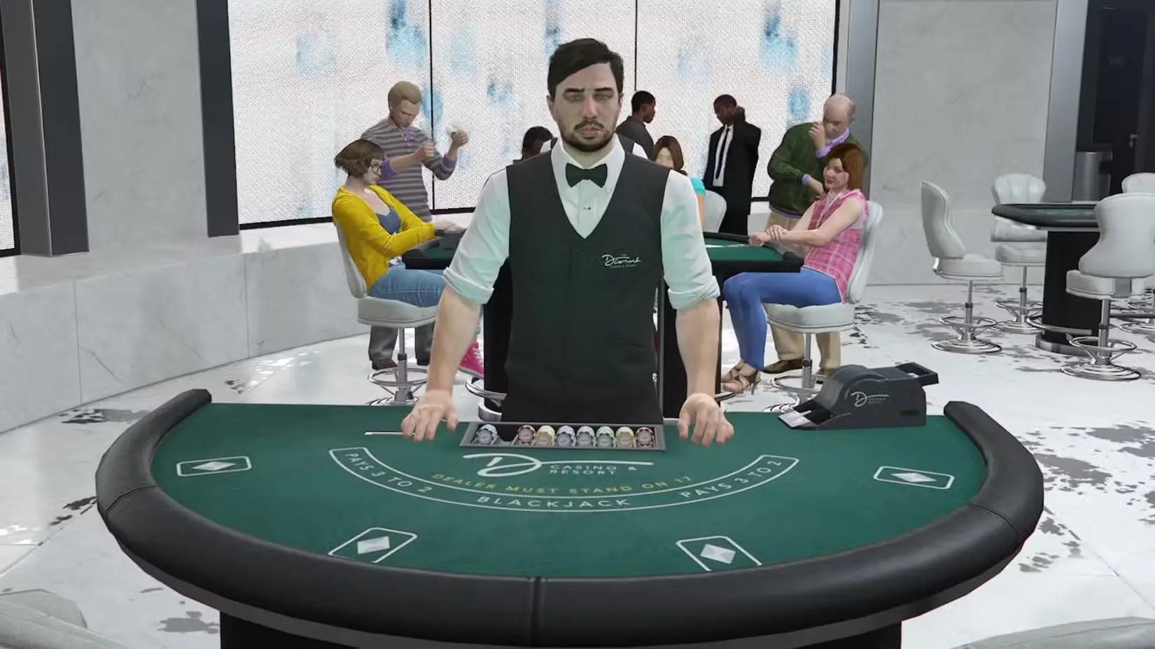 Dīleris baltā kreklā un melnā vestē stāv pie zaļa blekdžeka galda modernā kazino ar cilvēkiem fonā.