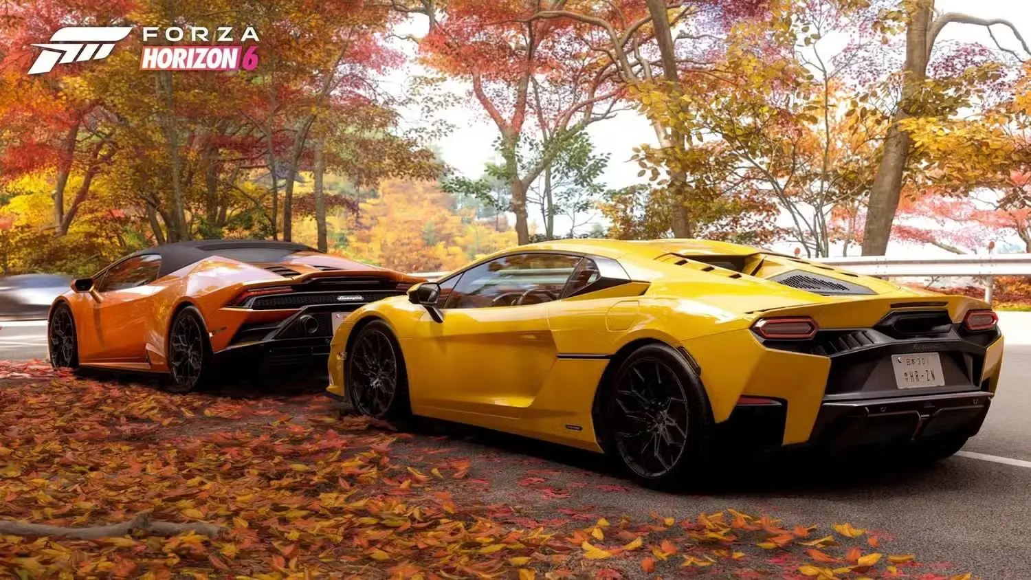 Divi eleganti un moderni Lamborghini superauto brauc pa asfaltētu ceļu. Viens auto ir dzeltens, bet otrs oranžs. Apkārt ir rudens ainava ar krāsainām koku lapām uz zemes.