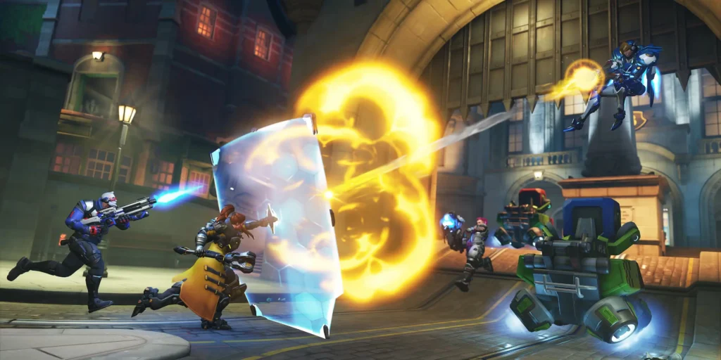 Vairāki Overwatch varoņi cīnās pilsētas ielās. Viens tēls aizsargājas ar lielu zilu vairogu, kamēr citi varoņi šauj un izmanto spējas, radot spilgtus sprādzienus.