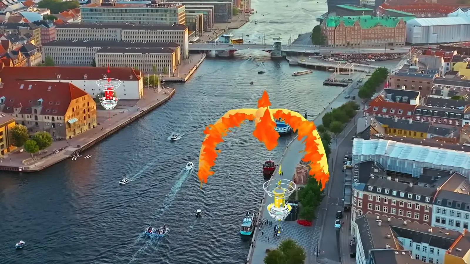 Skats no putna lidojuma uz pilsētas kanālu ar laivām un tiltiem, kur virs ūdens lido liels oranži dzeltens uguns putns virs diviem spēles torņiem.