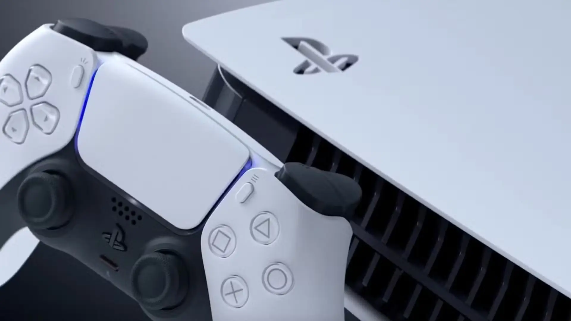 Balts PlayStation 5 bezvadu kontrolieris, kas novietots blakus baltai PlayStation 5 konsolei uz tumši pelēka fona.