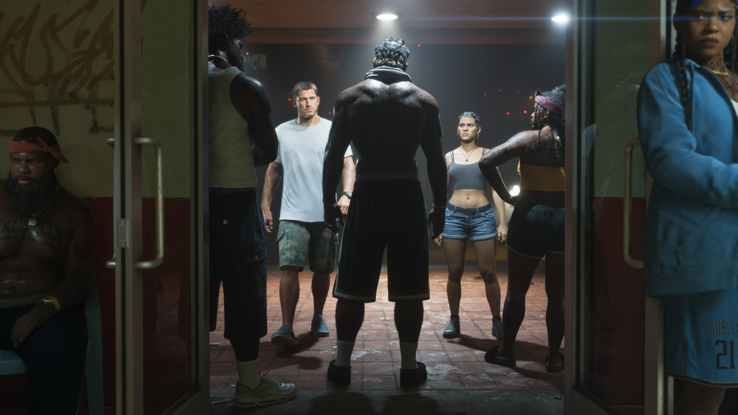 Vairāki tēli no spēles Grand Theft Auto 6 stāv iekštelpās vāji apgaismotā telpā un caur atvērtām stikla durvīm lūkojas ārā uz ielu.