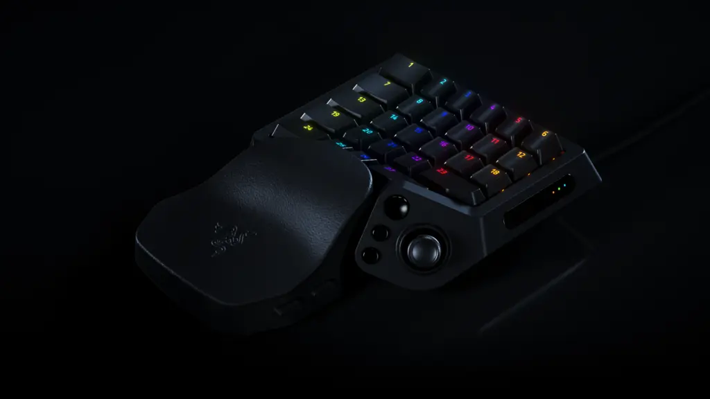 Melna Razer Tartarus V2 Pro spēļu tastatūra uz tumša fona, redzams regulējams plaukstas balsts, 24 izgaismoti taustiņi ar numuriem, sānu pogas un neliela īkšķa svira.