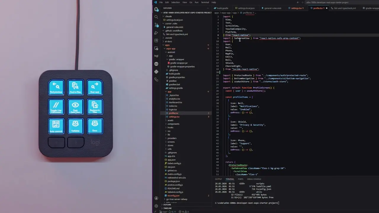 Kompakts Logitech MX Keypad ar izgaismotiem ziliem LCD taustiņiem, kas novietots blakus datora ekrānam ar atvērtu VS Code programmēšanas vidi un React Native kodu.